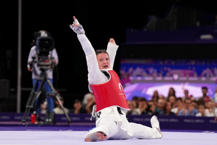 Amy Truesdale, a female Para taekwondo athlete, celebrates on the mat after winning a medal